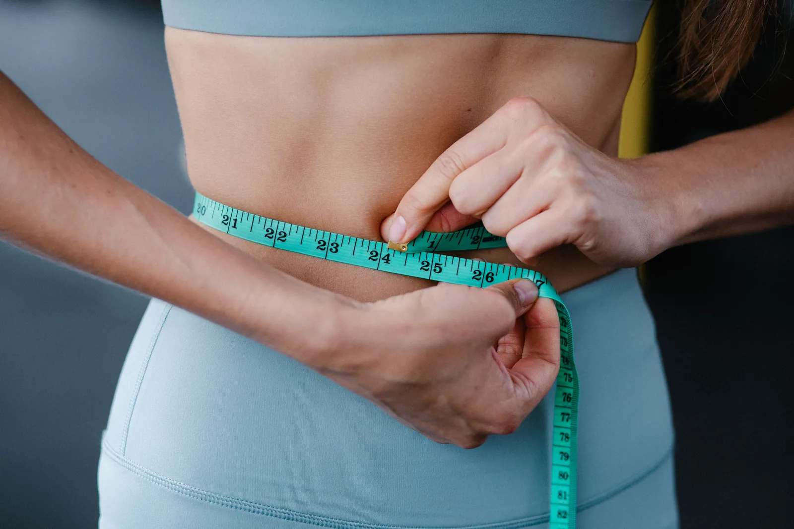 Waist measured with a teal tape measure